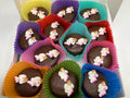 Chocolate candies with decorative figures in colorful paper cups on a white surface