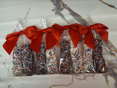 Packaged chocolate bars with sprinkles and a red ribbon on a marble surface